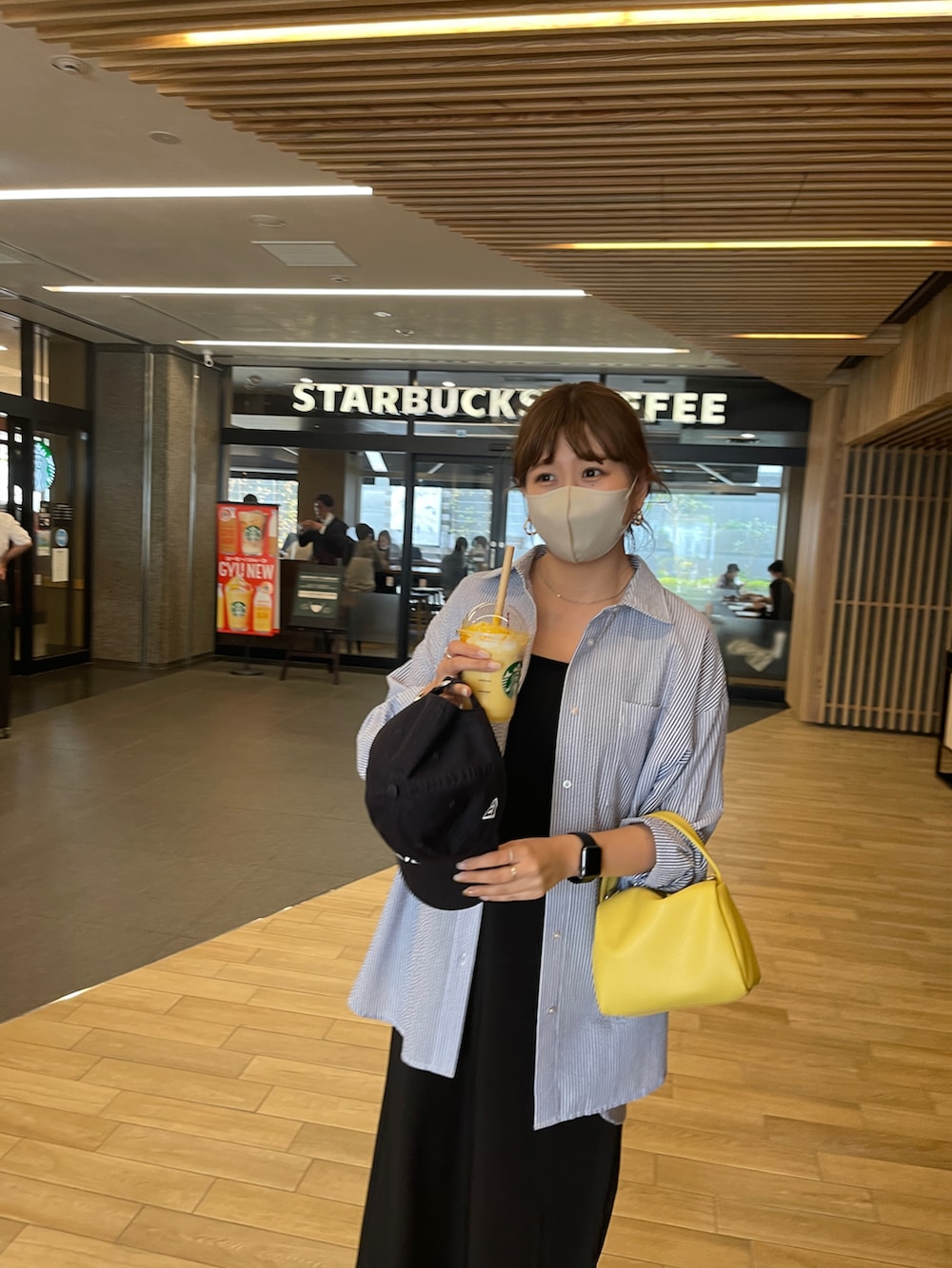 ブラック系のワンピース、ブラック系のサンダル、イエロー系のショルダーバッグを着用したレディースの春コーディネートの3枚目の写真