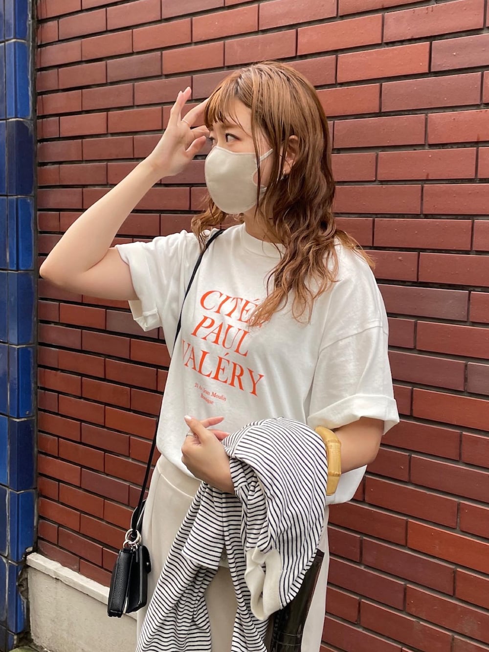 ブラック系のニット/セーター、オレンジ系のTシャツ/カットソー、ブラック系のショルダーバッグを着用したレディースの春コーディネートの3枚目の写真