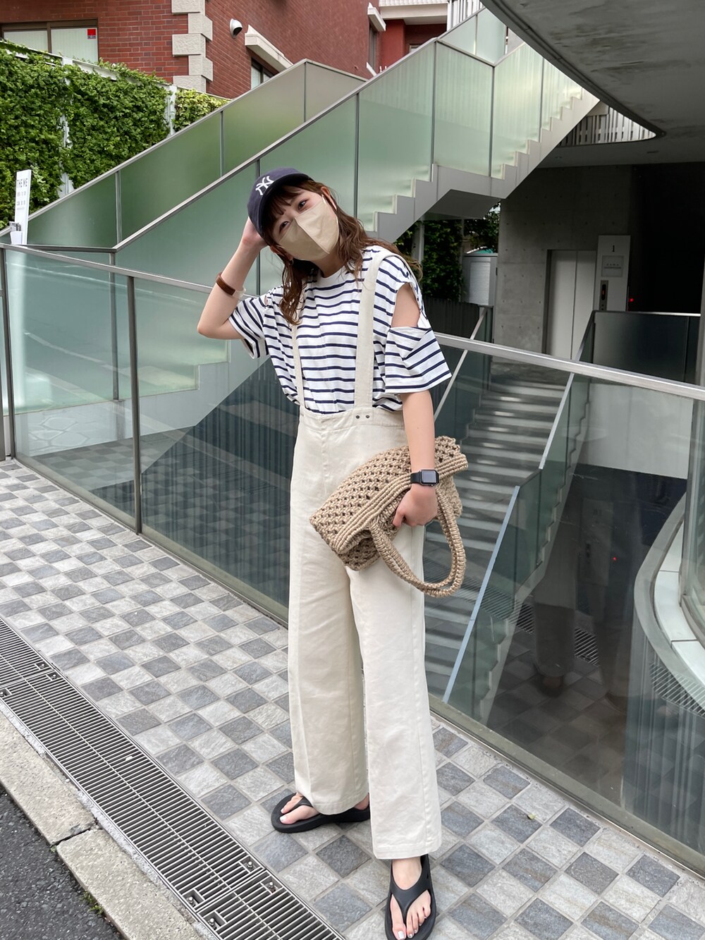 ブラック系のサンダル、ホワイト系のサロペット/オーバーオール、ベージュ系のトートバッグを着用したレディースの春コーディネートの3枚目の写真