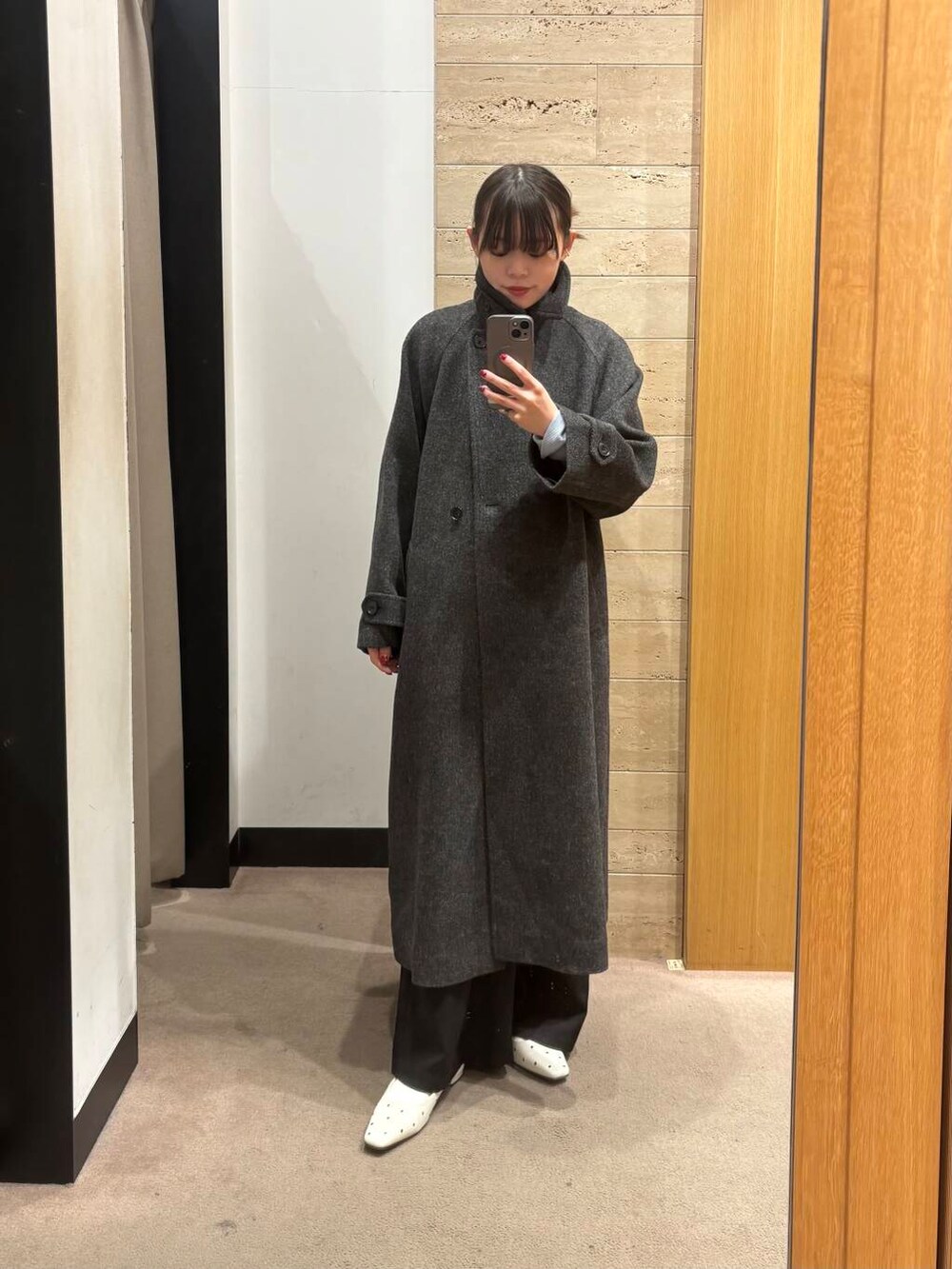 ブラック系のステンカラーコート、ブルー系のTシャツ/カットソー、ブラック系のその他パンツを着用したレディースの冬コーディネートの3枚目の写真