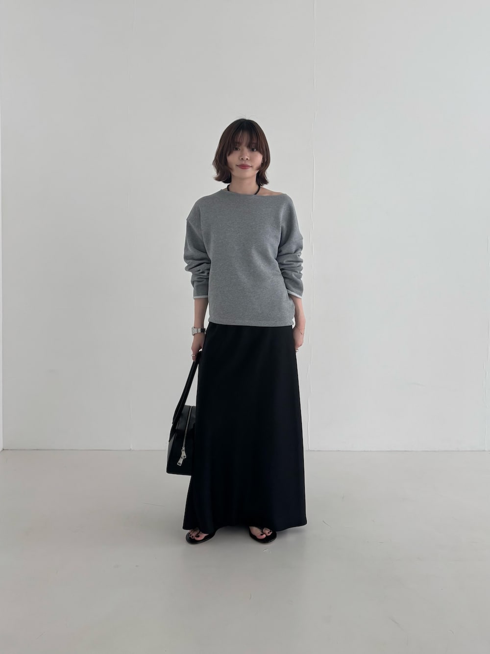 ブラック系のスカート、グレー系のスウェット、ブラック系のショルダーバッグを着用したレディースの春コーディネートの2枚目の写真