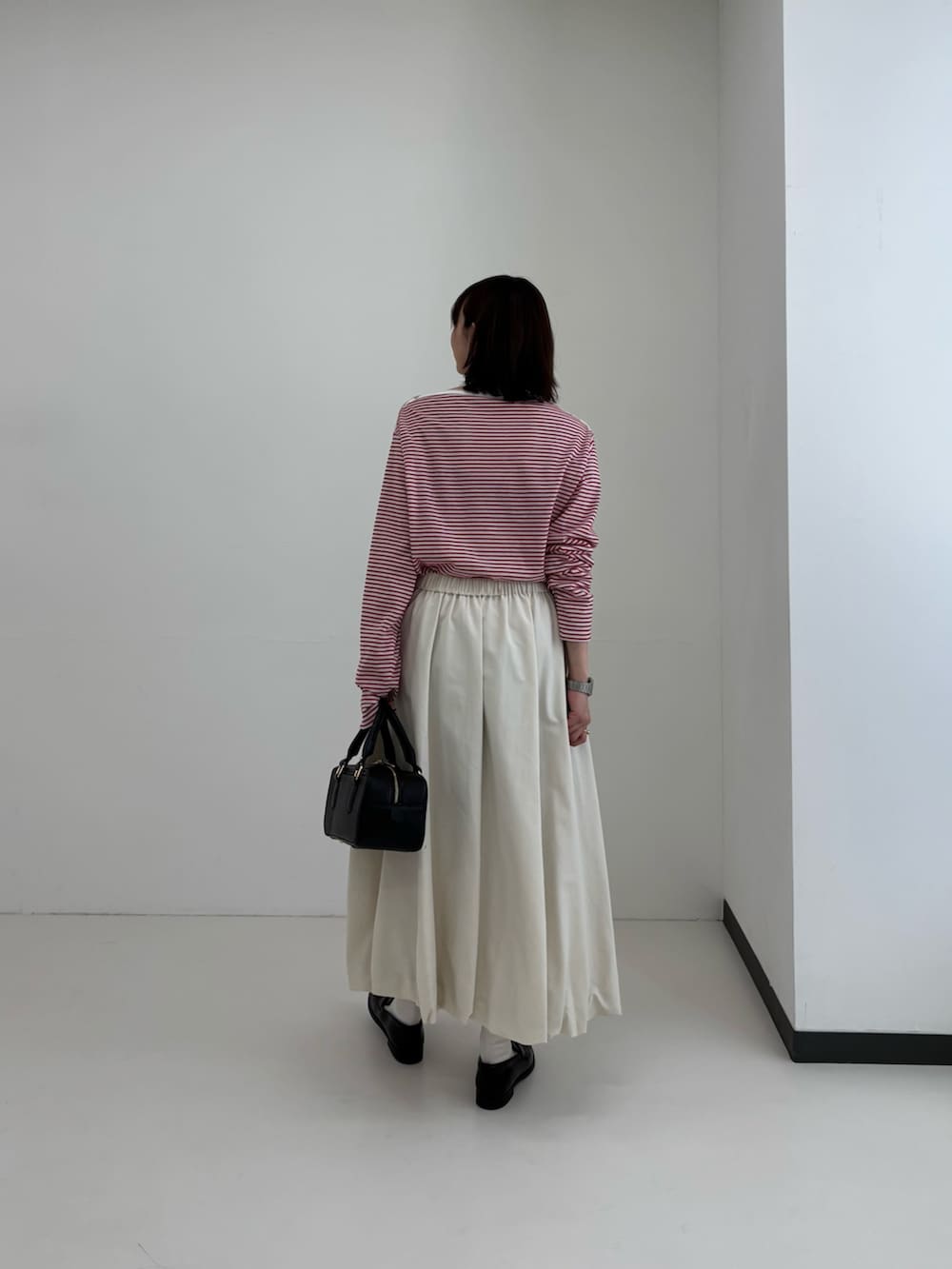 レッド系のTシャツ/カットソー、ホワイト系のスカート、シルバー系のネックレスを着用したレディースの春コーディネートの2枚目の写真