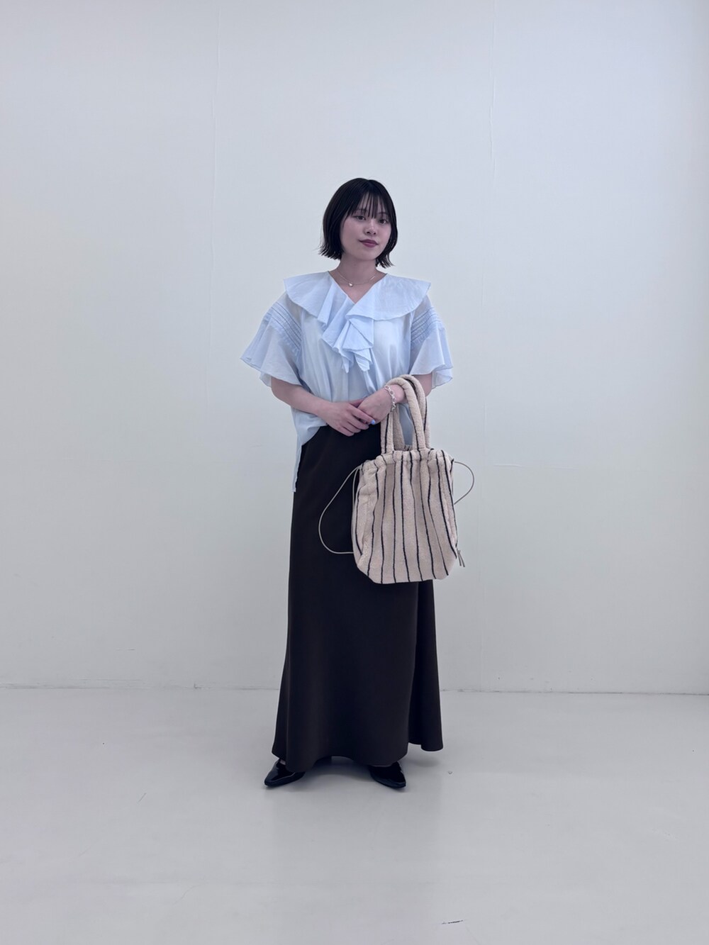 ブルー系のシャツ/ブラウス、ホワイト系のハンドバッグ、ブラウン系のスカートを着用したレディースの夏コーディネートの2枚目の写真