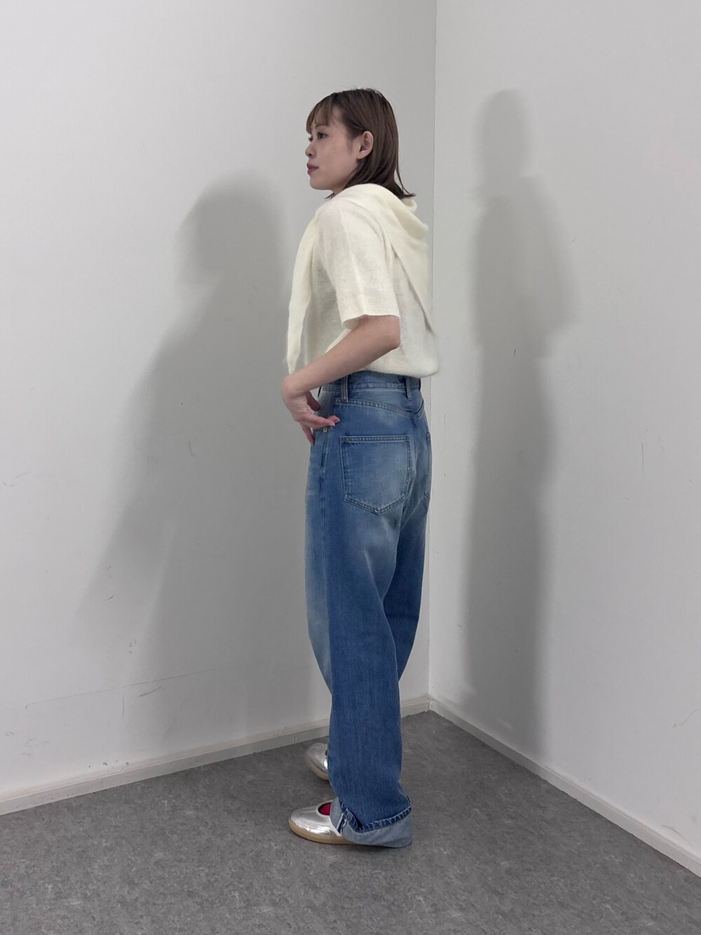 ホワイト系のニット/セーター、ブルー系のデニムパンツ、シルバー系のスニーカーを着用したレディースの秋コーディネートの2枚目の写真