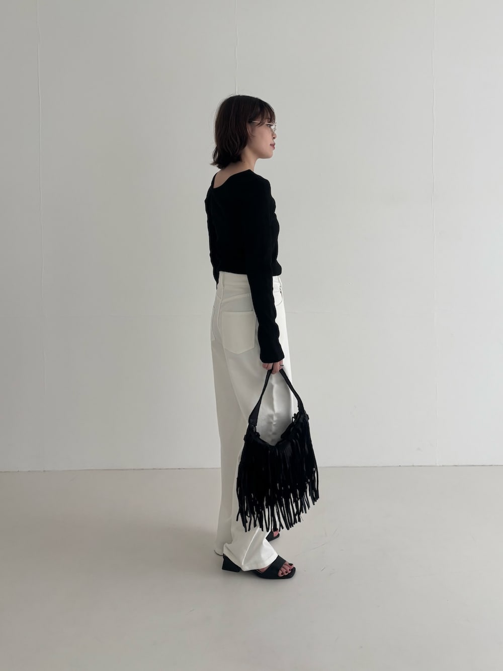 ホワイト系のデニムパンツ、ブラック系のTシャツ/カットソー、ブラック系のハンドバッグを着用したレディースの春コーディネートの2枚目の写真