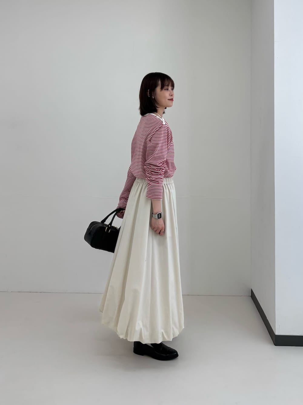 レッド系のTシャツ/カットソー、ホワイト系のスカート、シルバー系のネックレスを着用したレディースの春コーディネートの3枚目の写真