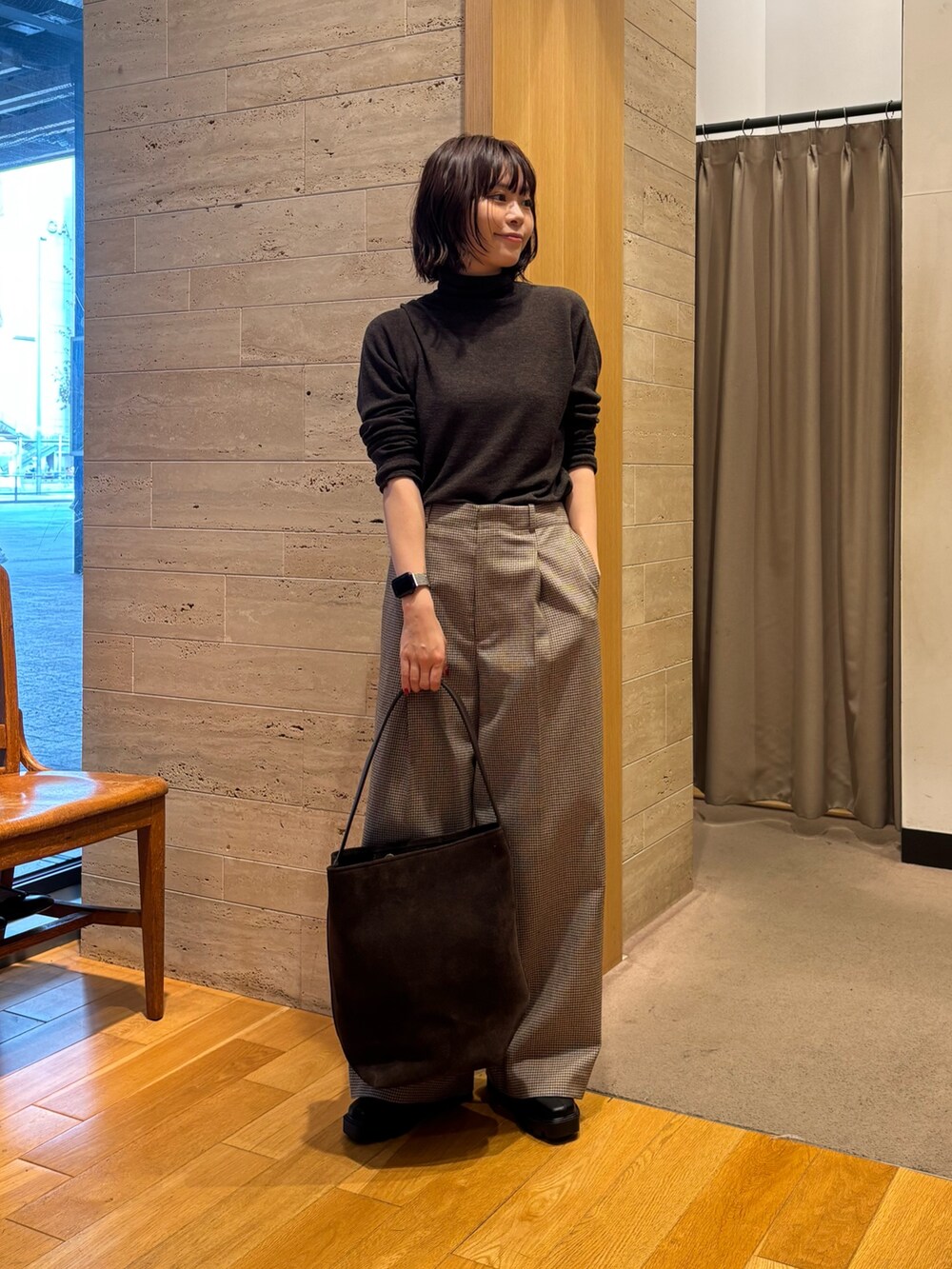 グリーン系のニット/セーター、ブラウン系のステンカラーコート、ブラウン系のトートバッグを着用したレディースの秋コーディネートの3枚目の写真