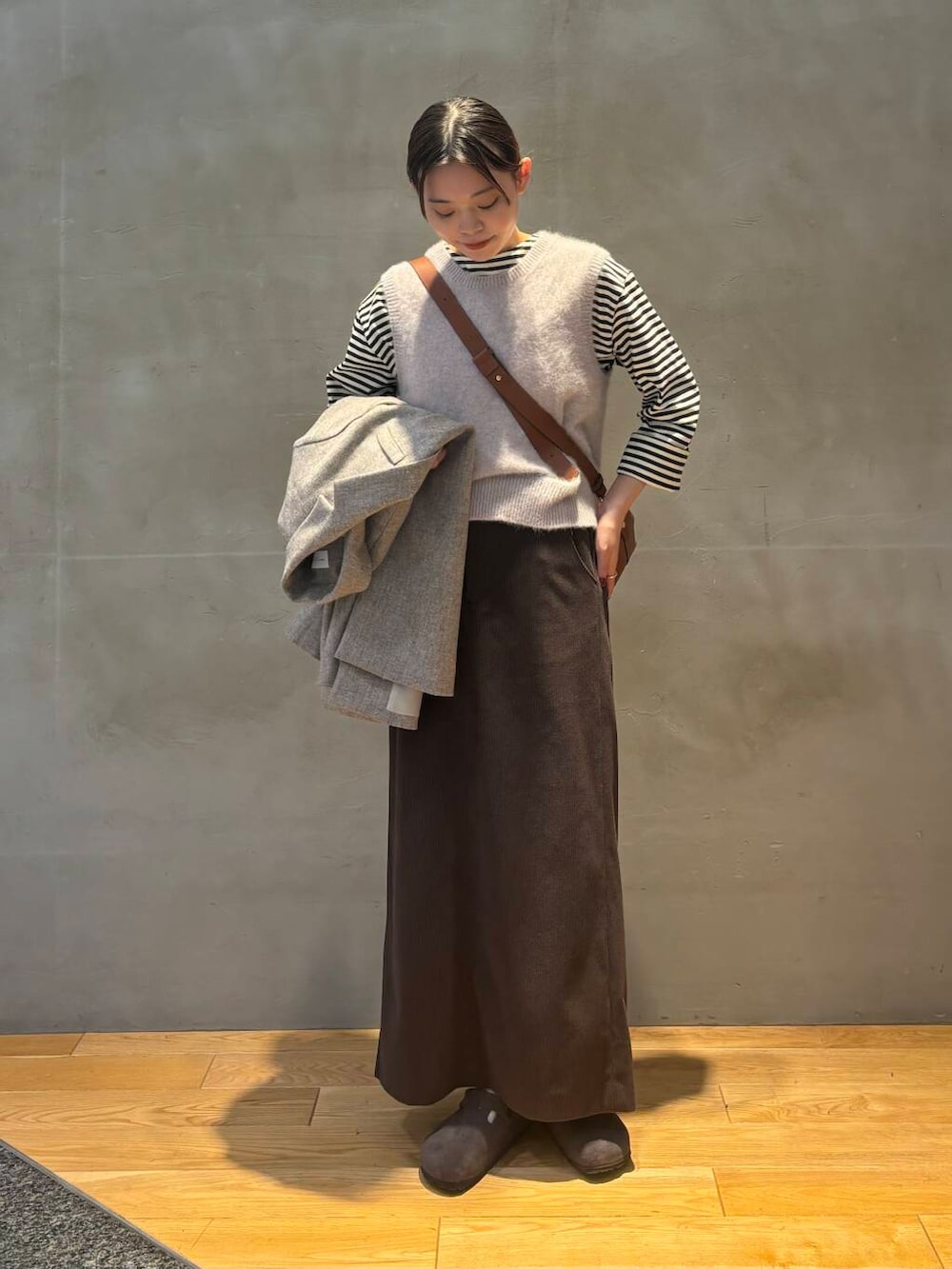 ブラウン系のスカート、グレー系のベスト、ホワイト系のTシャツ/カットソーを着用したレディースの秋コーディネートの5枚目の写真