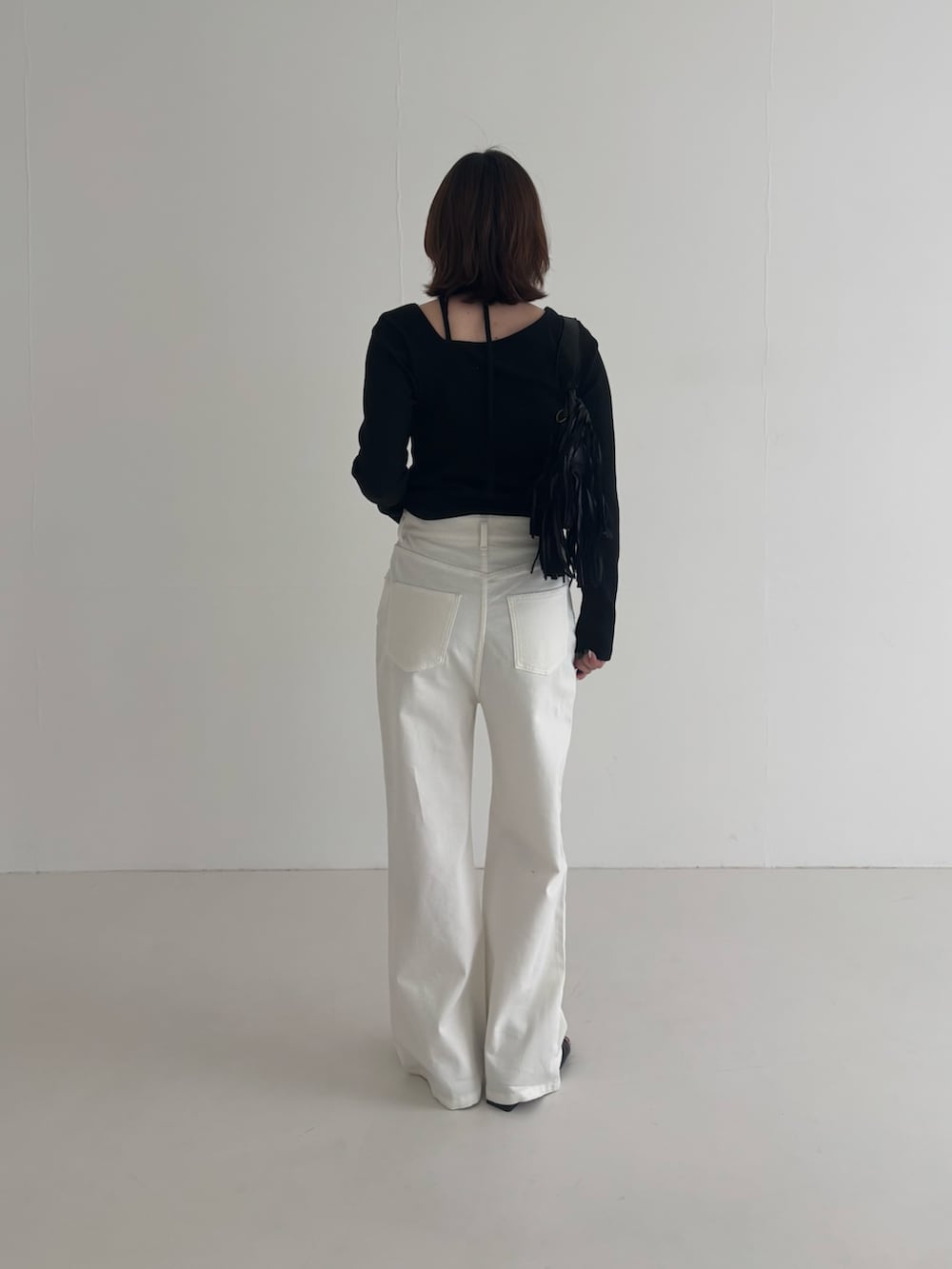 ホワイト系のデニムパンツ、ブラック系のTシャツ/カットソー、ブラック系のハンドバッグを着用したレディースの春コーディネートの3枚目の写真