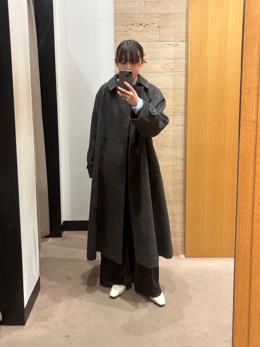 ブラック系のステンカラーコート、ブルー系のTシャツ/カットソー、ブラック系のその他パンツを着用したレディースの冬コーディネートの2枚目の写真