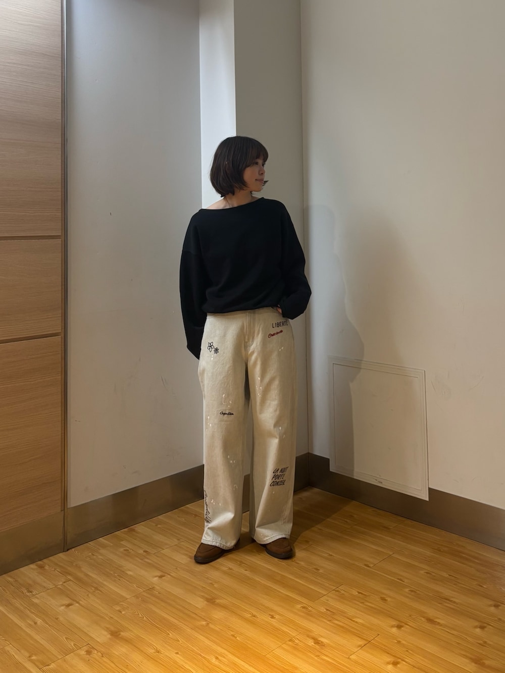 グレー系のデニムパンツ、ブラック系のスウェット、イエロー系のローファーを着用したレディースの冬コーディネートの2枚目の写真