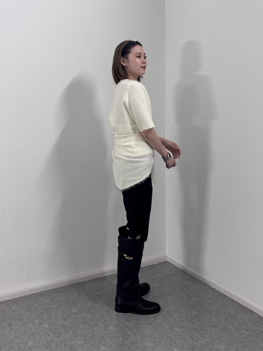 ホワイト系のニット/セーター、ブラック系のその他パンツ、ブラック系のブーツを着用したレディースの秋コーディネートの2枚目の写真