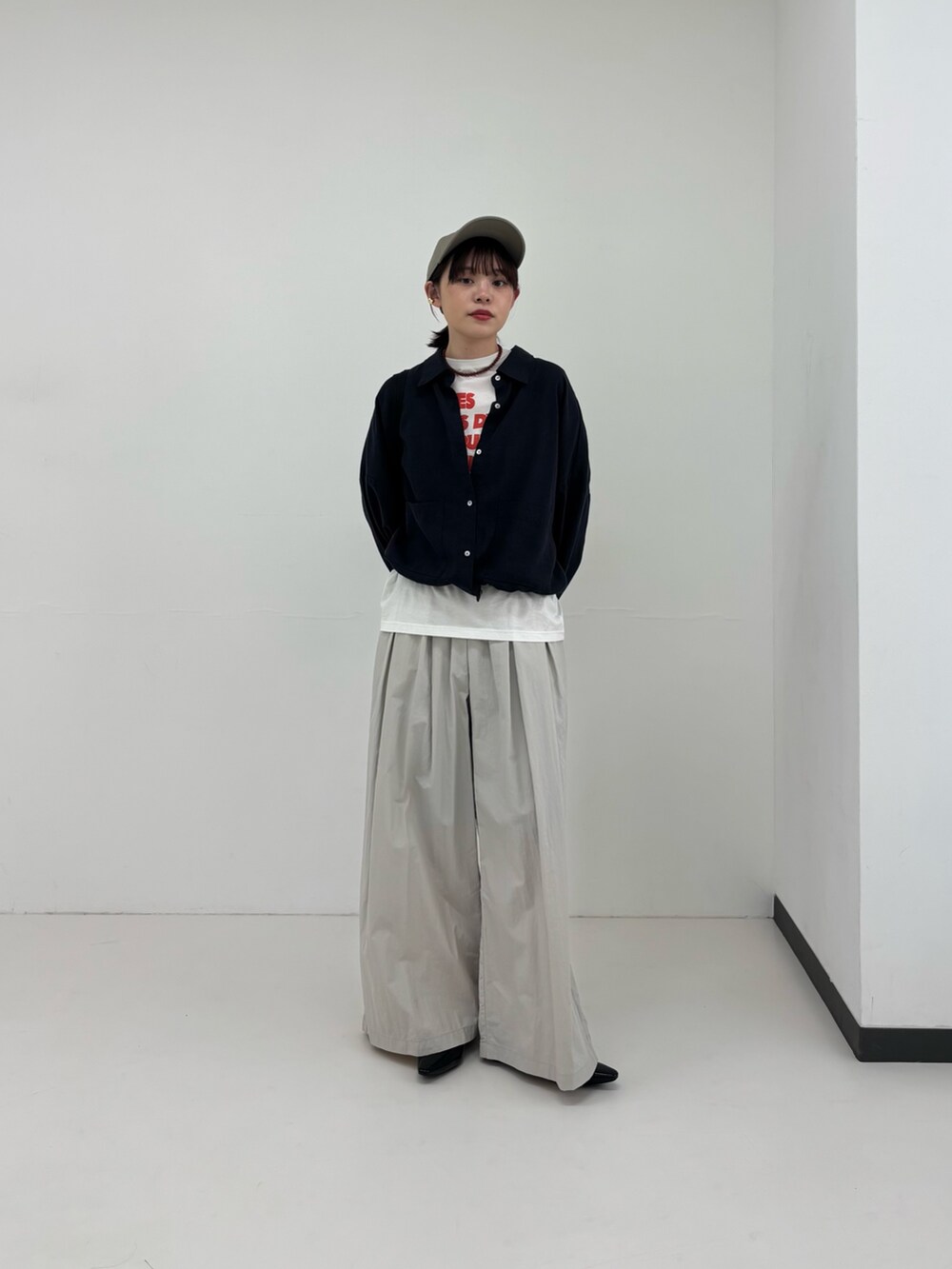 ブラック系のバックパック/リュック、ブラック系のパンプス、ブルー系のシャツ/ブラウスを着用したレディースの春コーディネートの2枚目の写真