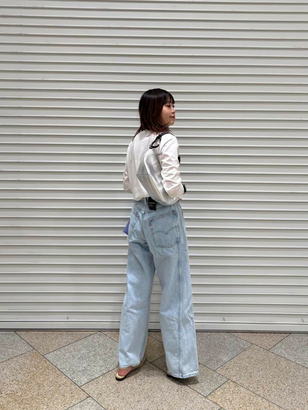 ホワイト系のTシャツ/カットソー、ベージュ系のパンプス、ブルー系のデニムパンツを着用したレディースの冬コーディネートの6枚目の写真