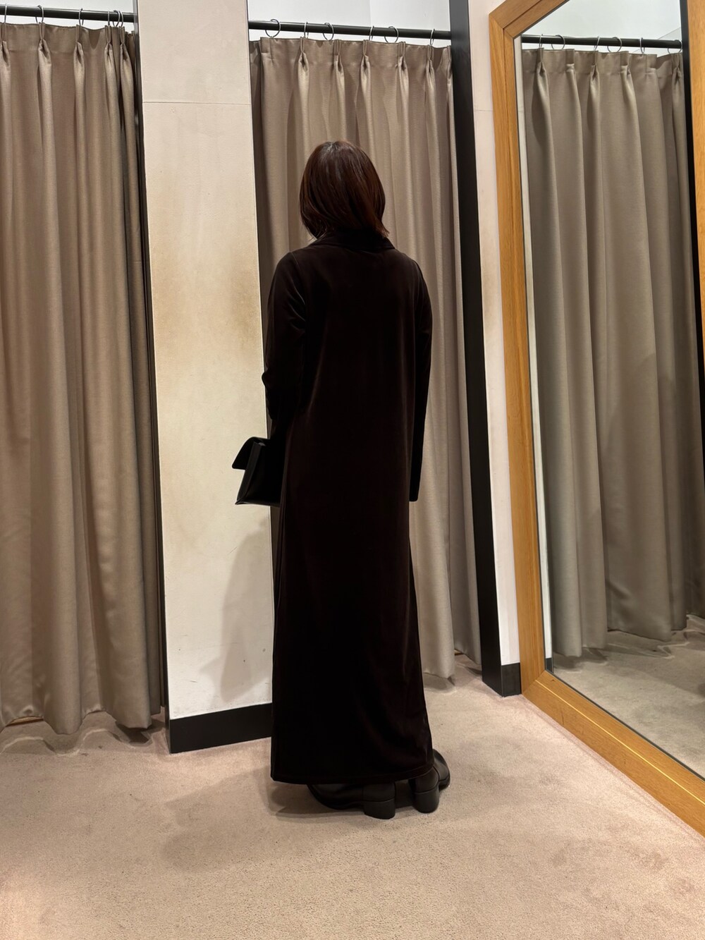 ブラウン系のワンピース、ブラック系のハンドバッグ、ブラック系のブーツを着用したレディースの秋コーディネートの3枚目の写真