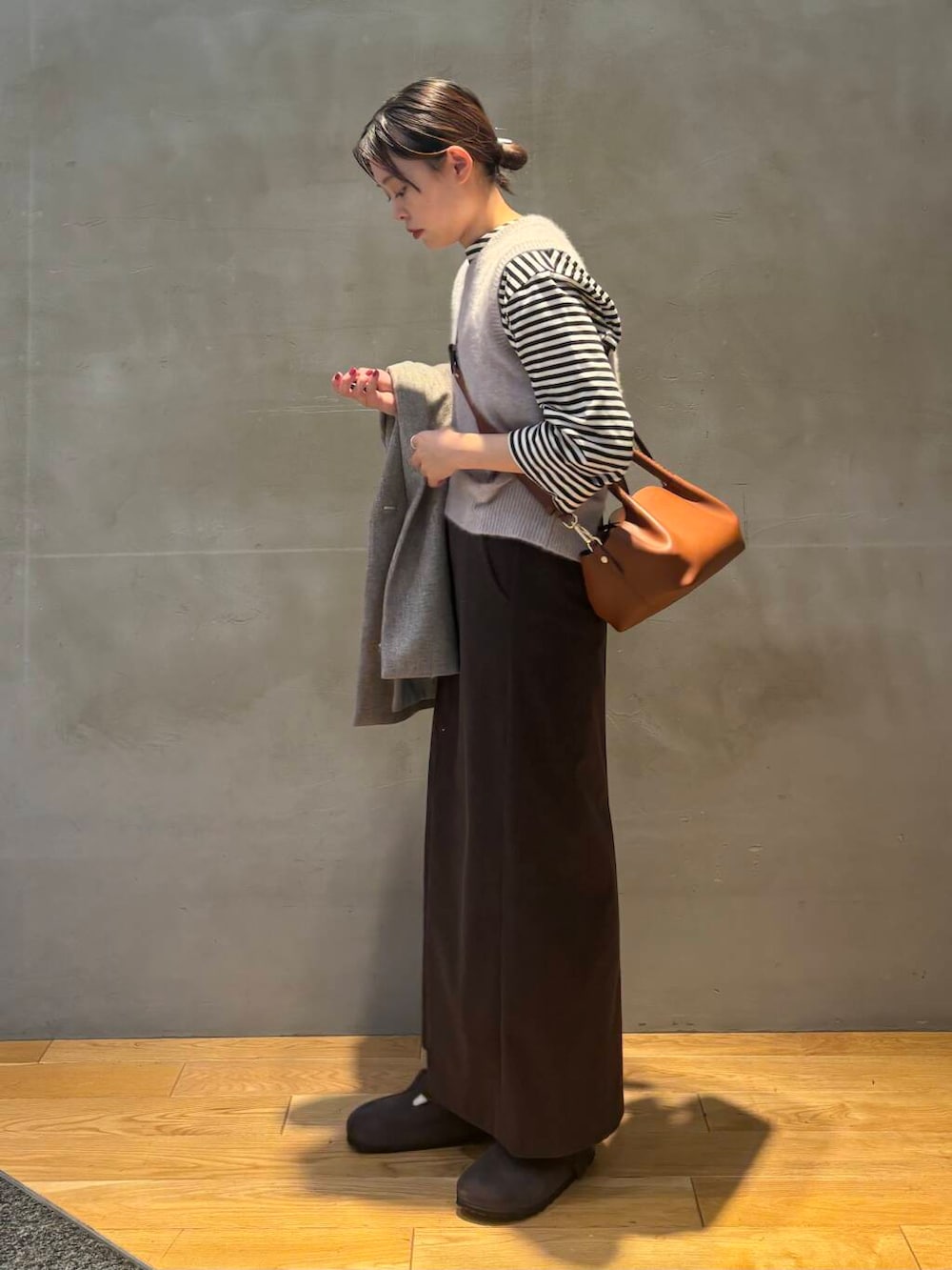 ブラウン系のスカート、グレー系のベスト、ホワイト系のTシャツ/カットソーを着用したレディースの秋コーディネートの4枚目の写真