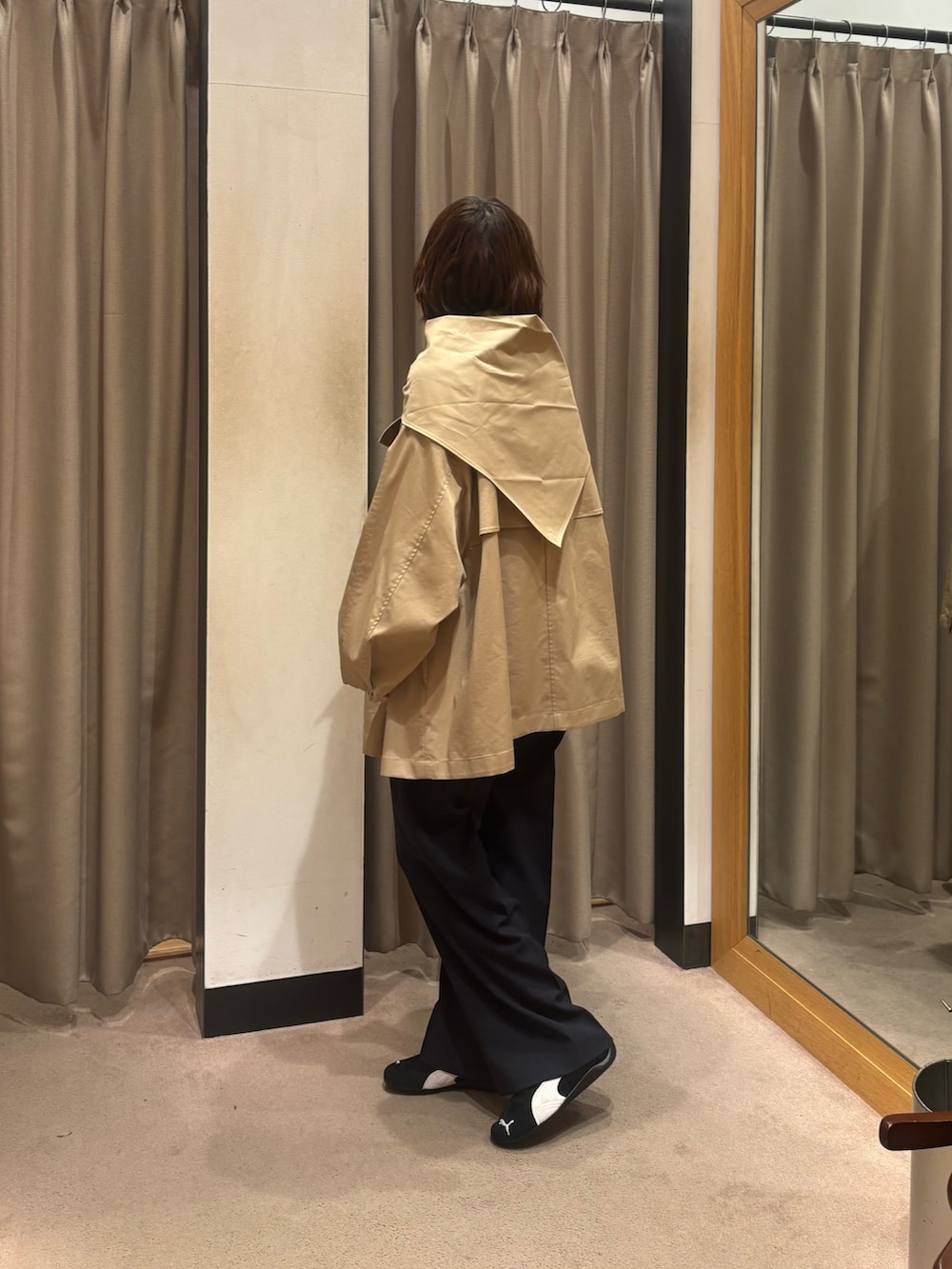 ベージュ系のトレンチコート、ブルー系のその他パンツ、ブラック系のスニーカーを着用したレディースの冬コーディネートの2枚目の写真