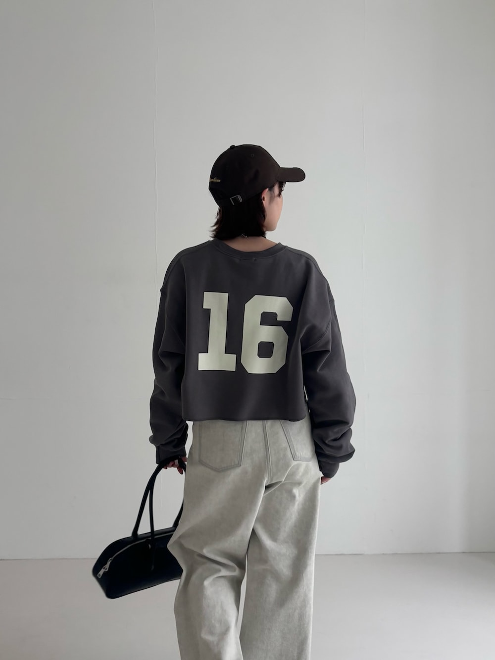 グレー系のデニムパンツ、ブラウン系のスニーカー、グレー系のスウェットを着用したレディースの春コーディネートの5枚目の写真