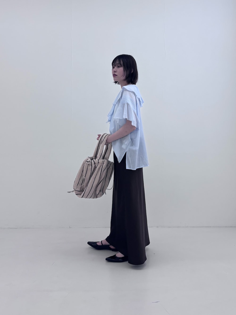 ブルー系のシャツ/ブラウス、ホワイト系のハンドバッグ、ブラウン系のスカートを着用したレディースの夏コーディネートの3枚目の写真