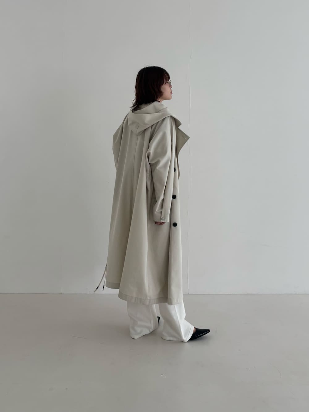 ベージュ系のトレンチコート、ブラック系のパンプス、ホワイト系のスウェットを着用したレディースの春コーディネートの2枚目の写真