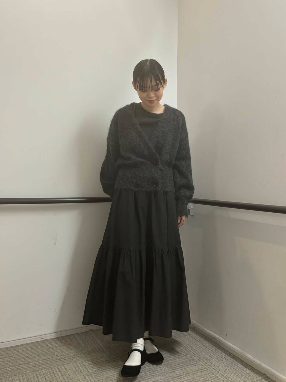 ブラック系のスカート、グリーン系のニット/セーター、グレー系のカーディガン/ボレロを着用したレディースの秋コーディネートの2枚目の写真