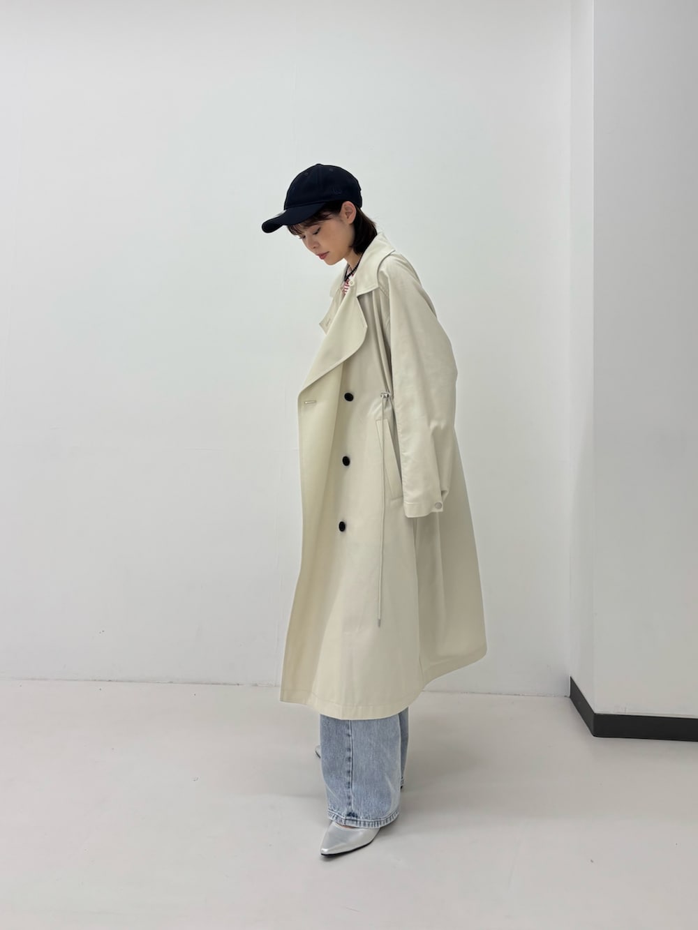 ベージュ系のトレンチコート、ブルー系のデニムパンツ、レッド系のTシャツ/カットソーを着用したレディースの春コーディネートの2枚目の写真