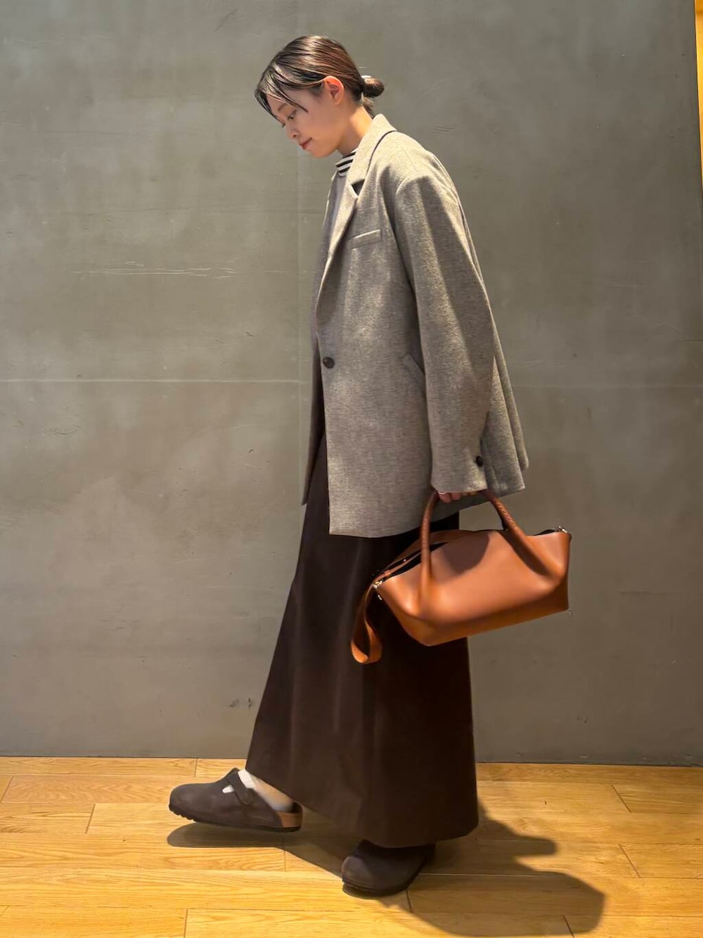 ブラウン系のスカート、グレー系のベスト、ホワイト系のTシャツ/カットソーを着用したレディースの秋コーディネートの3枚目の写真