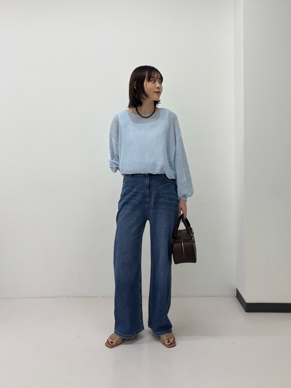 ブルー系のニット/セーター、ホワイト系のタンクトップ、ブルー系のデニムパンツを着用したレディースの春コーディネートの2枚目の写真