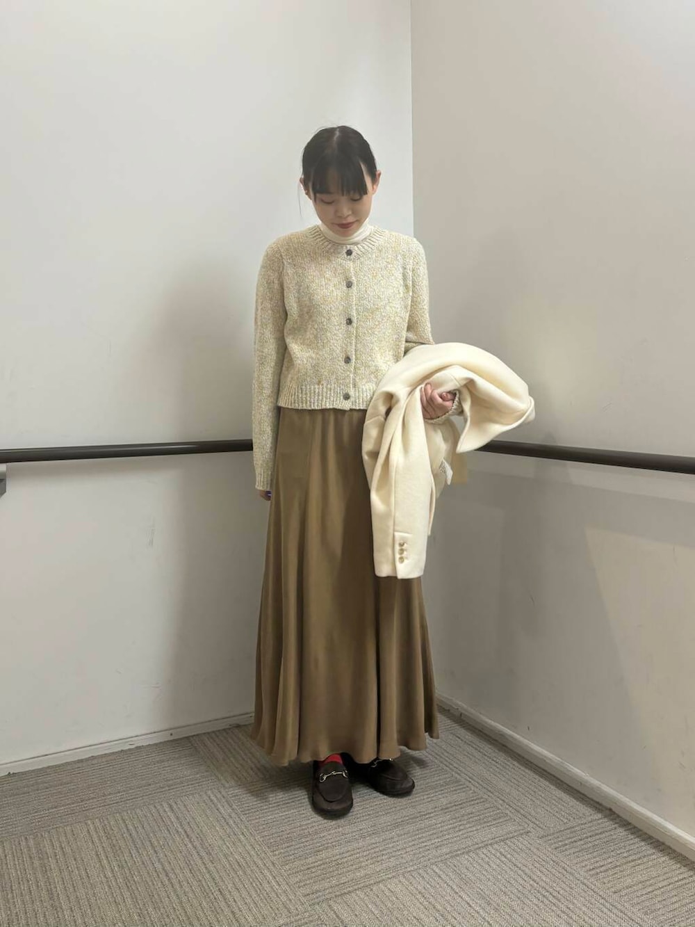 ホワイト系のその他アウター、イエロー系のスカート、ホワイト系のカーディガン/ボレロを着用したレディースの冬コーディネートの6枚目の写真