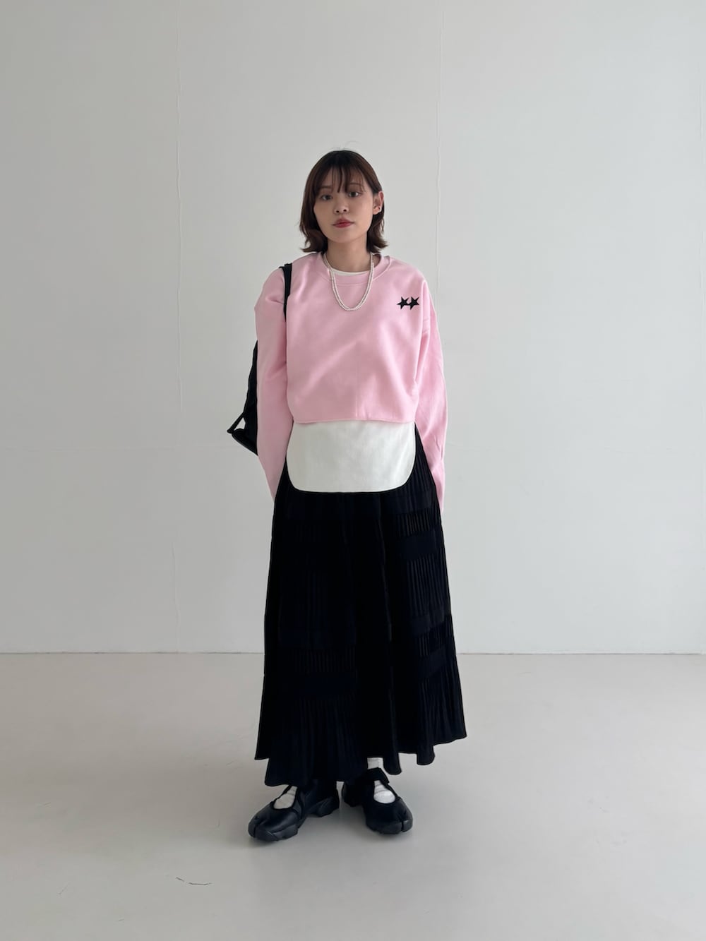 ブラック系のスニーカー、ブラック系のバックパック/リュック、ピンク系のスウェットを着用したレディースの春コーディネートの3枚目の写真