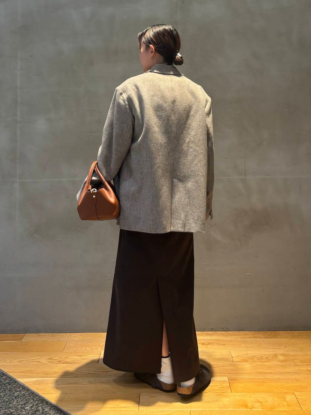 ブラウン系のスカート、グレー系のベスト、ホワイト系のTシャツ/カットソーを着用したレディースの秋コーディネートの2枚目の写真