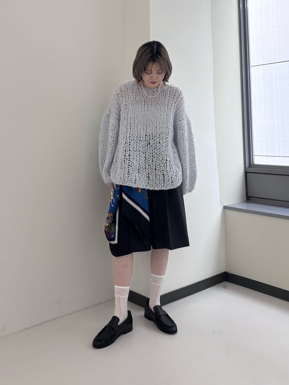 ブルー系のニット/セーター、グレー系のその他パンツ、ブラック系のローファーを着用したレディースの秋コーディネートの2枚目の写真