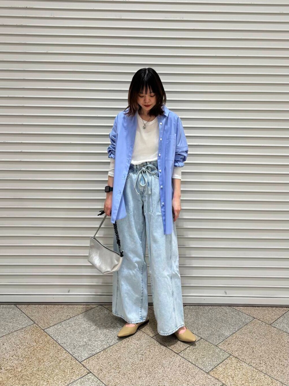 ホワイト系のTシャツ/カットソー、ベージュ系のパンプス、ブルー系のデニムパンツを着用したレディースの冬コーディネートの3枚目の写真