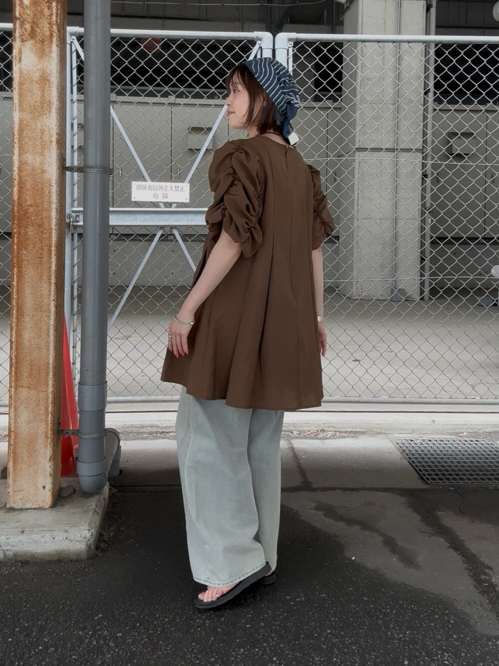 ブラウン系のワンピース、ブルー系のデニムパンツを着用したレディースの春コーディネートの3枚目の写真