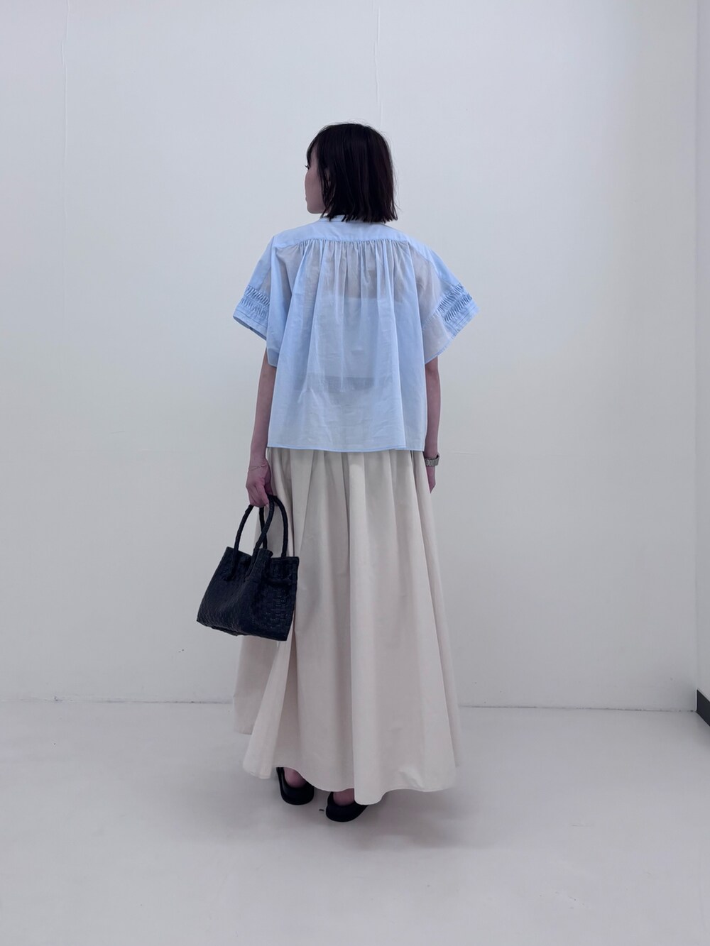 ブルー系のシャツ/ブラウス、ホワイト系のスカート、ブラック系のサンダルを着用したレディースの夏コーディネートの2枚目の写真