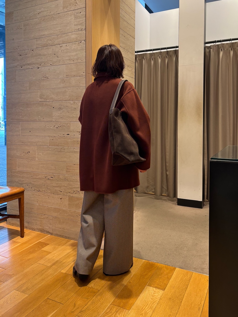 グリーン系のニット/セーター、ブラウン系のステンカラーコート、ブラウン系のトートバッグを着用したレディースの秋コーディネートの2枚目の写真