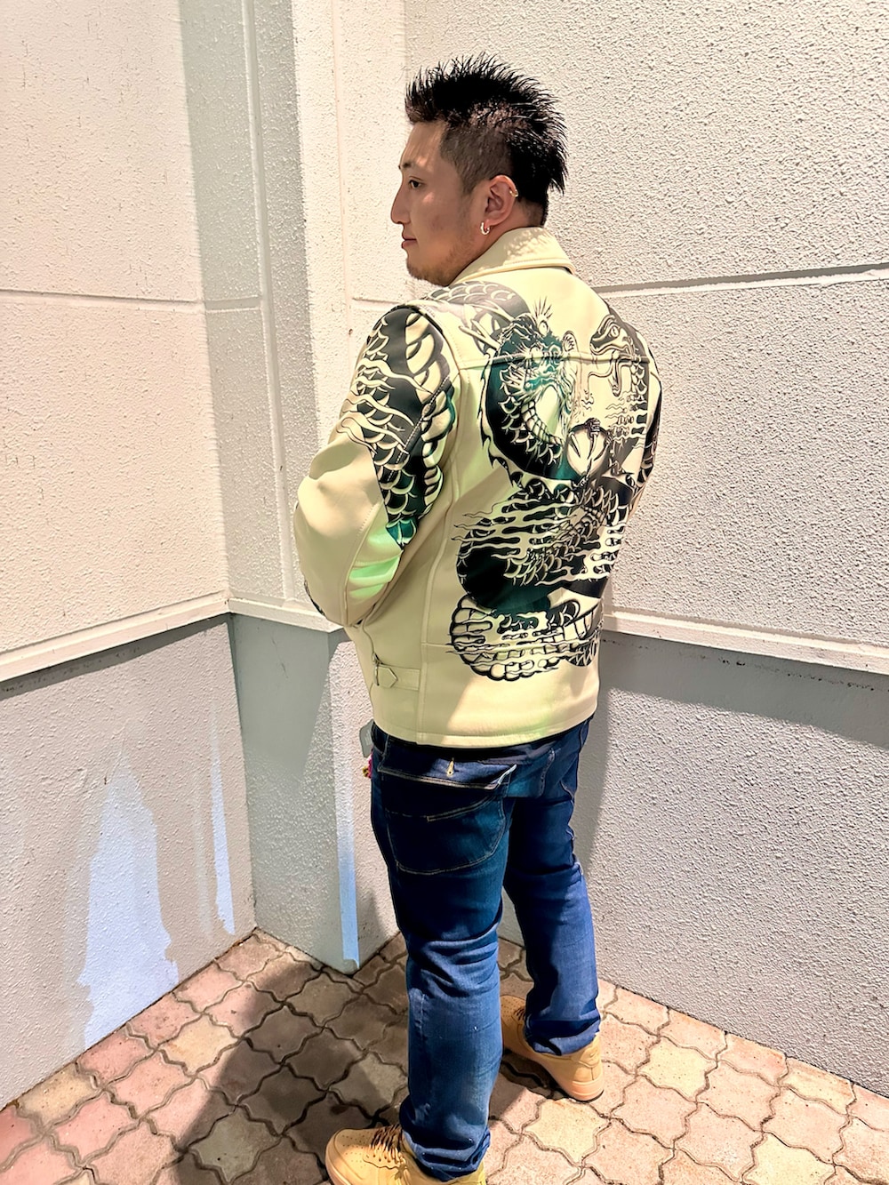 ホワイト系のライダースジャケット、ブラック系のタンクトップ、ブルー系のデニムパンツを着用したメンズの冬コーディネートの4枚目の写真