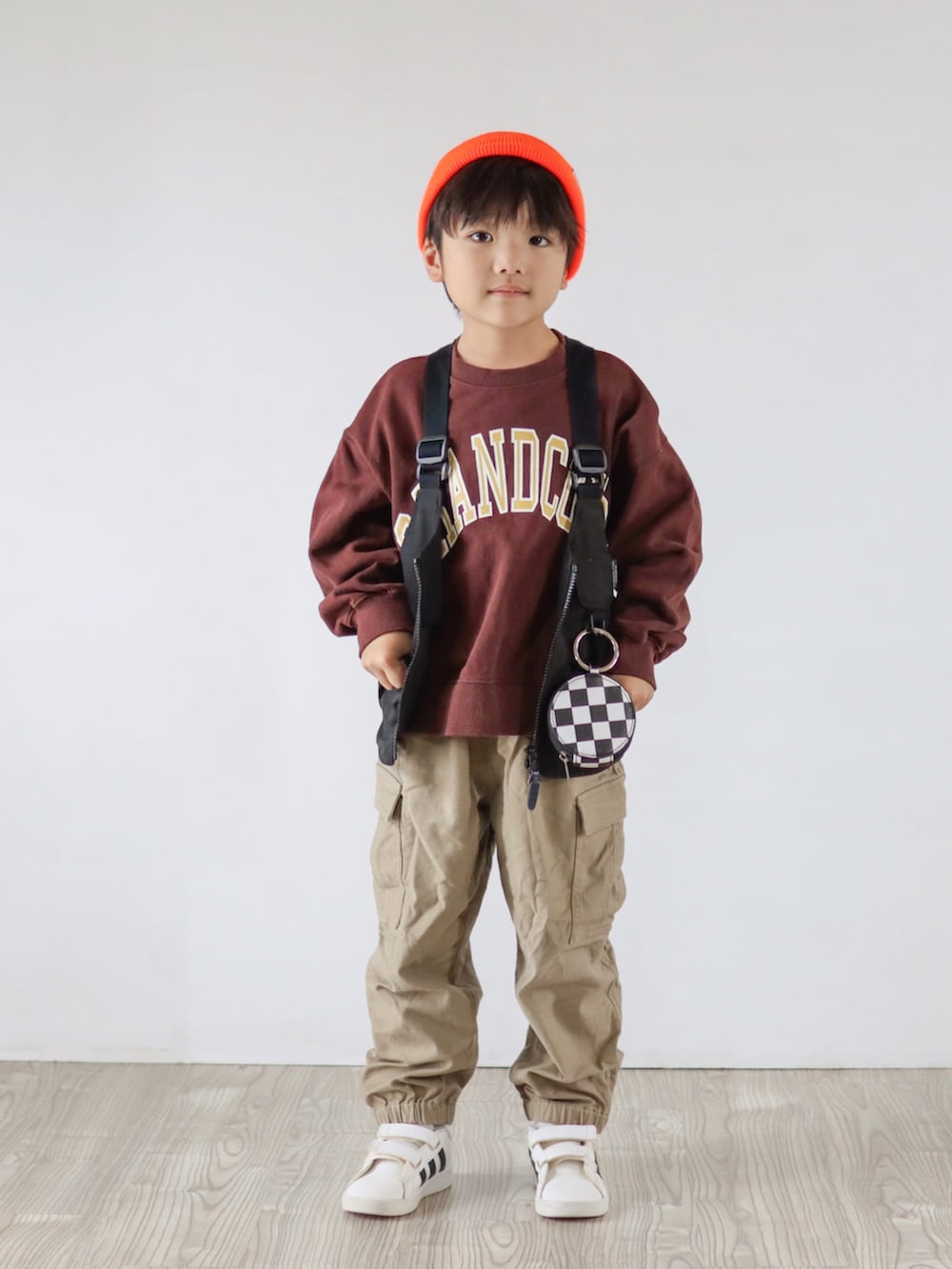 ブラウン系のスウェット、ブラック系のベスト、ベージュ系のカーゴパンツを着用したキッズの秋コーディネートの2枚目の写真
