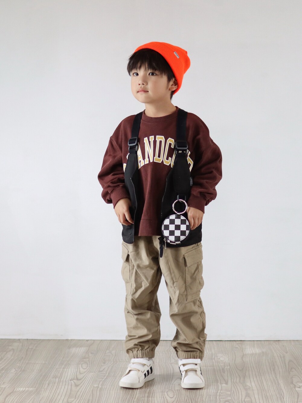 ブラウン系のスウェット、ブラック系のベスト、ベージュ系のカーゴパンツを着用したキッズの秋コーディネートの3枚目の写真