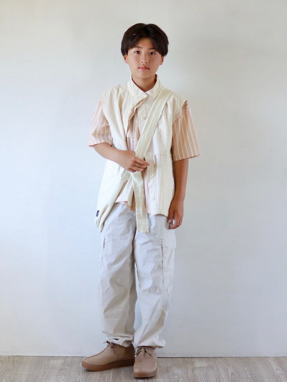 オレンジ系のシャツ/ブラウス、ホワイト系のベスト、ブラック系のカーゴパンツを着用したキッズの春コーディネートの2枚目の写真