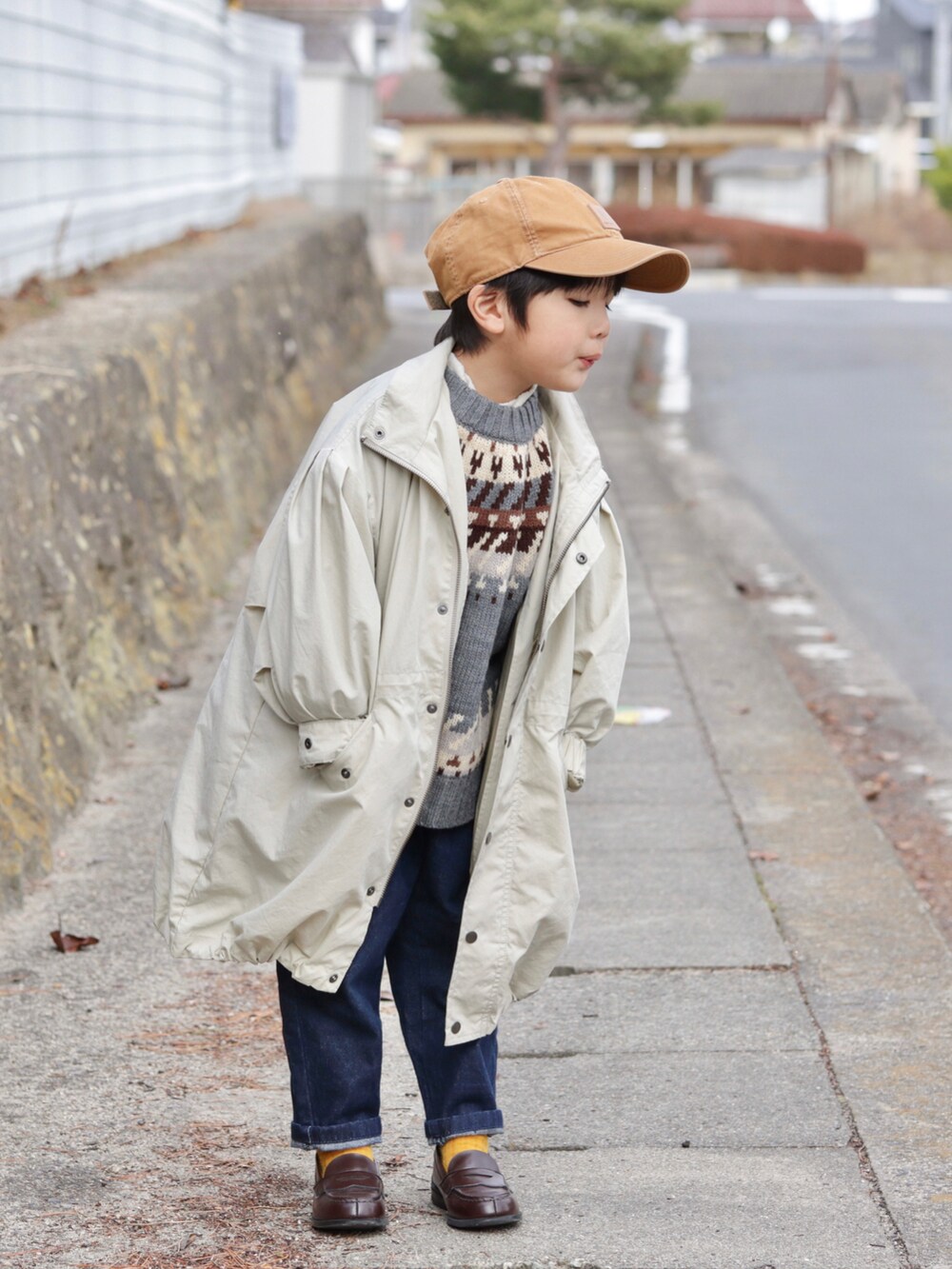 ベージュ系のモッズコート、グレー系のニット/セーター、ブルー系のデニムパンツを着用したキッズの冬コーディネートの4枚目の写真