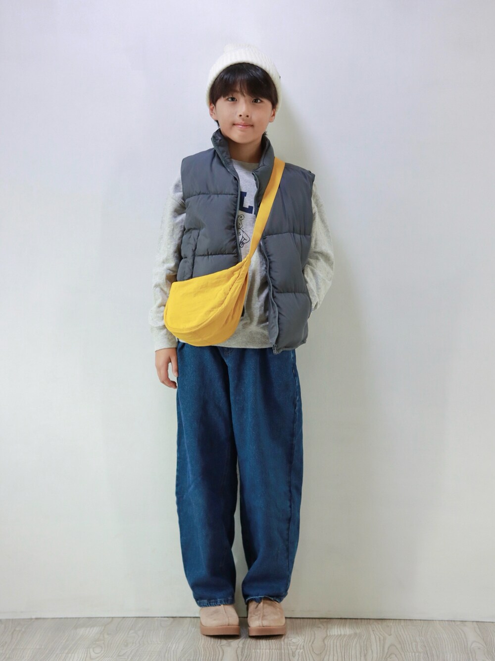 ホワイト系のスウェット、グレー系のダウンベスト、ブルー系のデニムパンツを着用したキッズの冬コーディネートの3枚目の写真