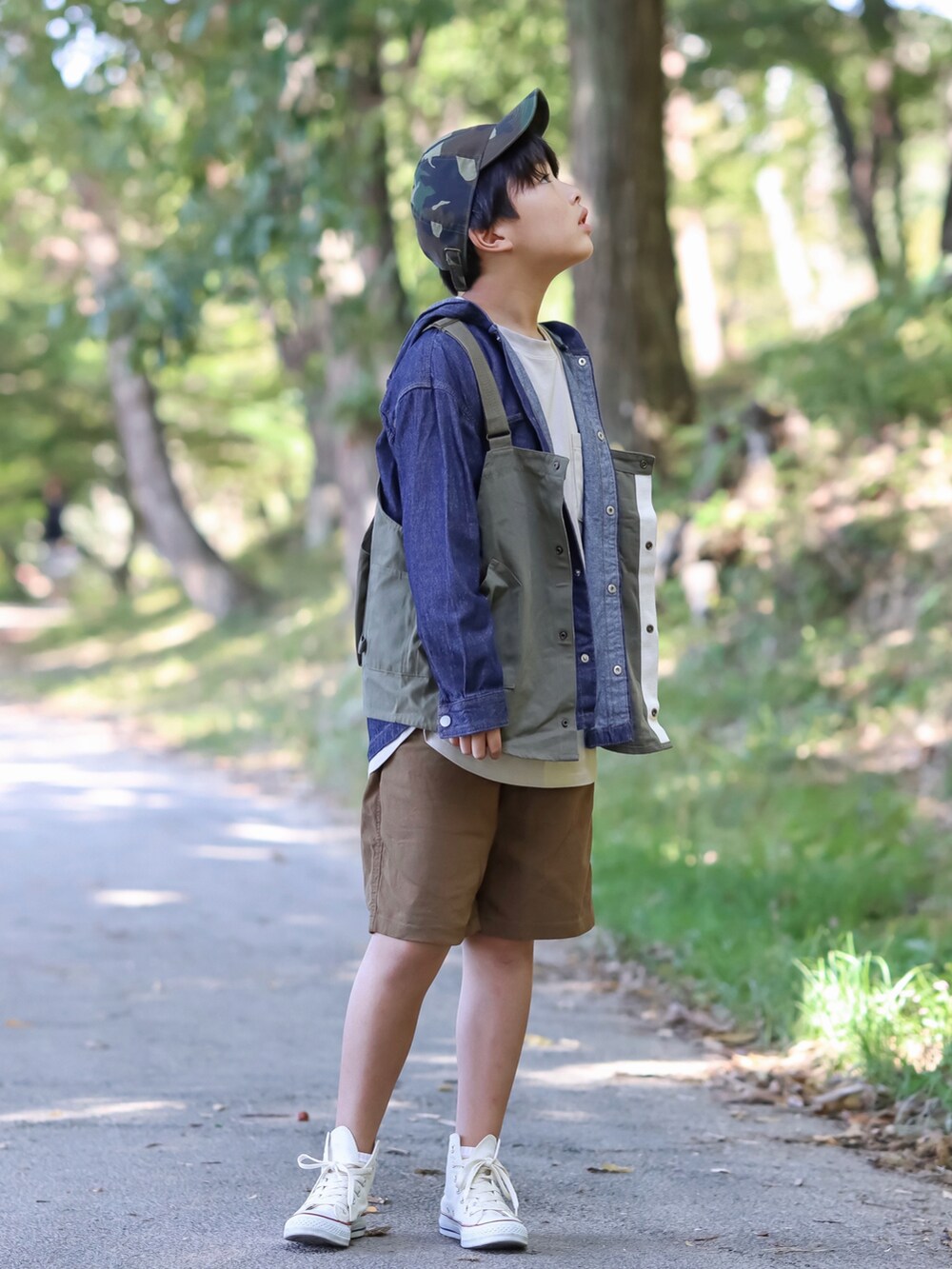 グリーン系のベスト、ベージュ系のチノパンツ、ホワイト系のスニーカーを着用したキッズの秋コーディネートの3枚目の写真