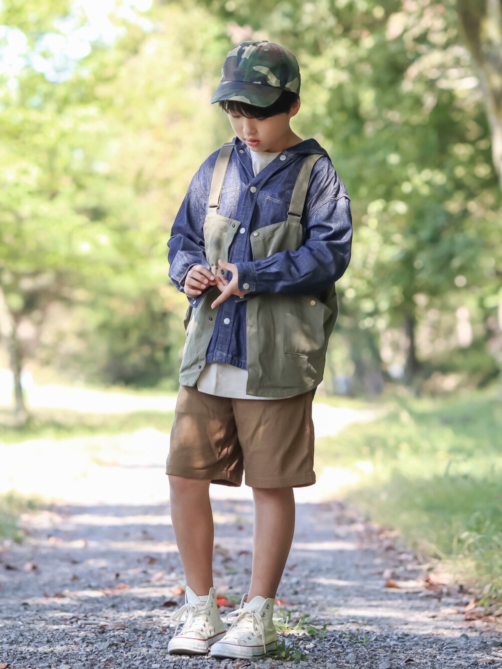 グリーン系のベスト、ベージュ系のチノパンツ、ホワイト系のスニーカーを着用したキッズの秋コーディネートの2枚目の写真