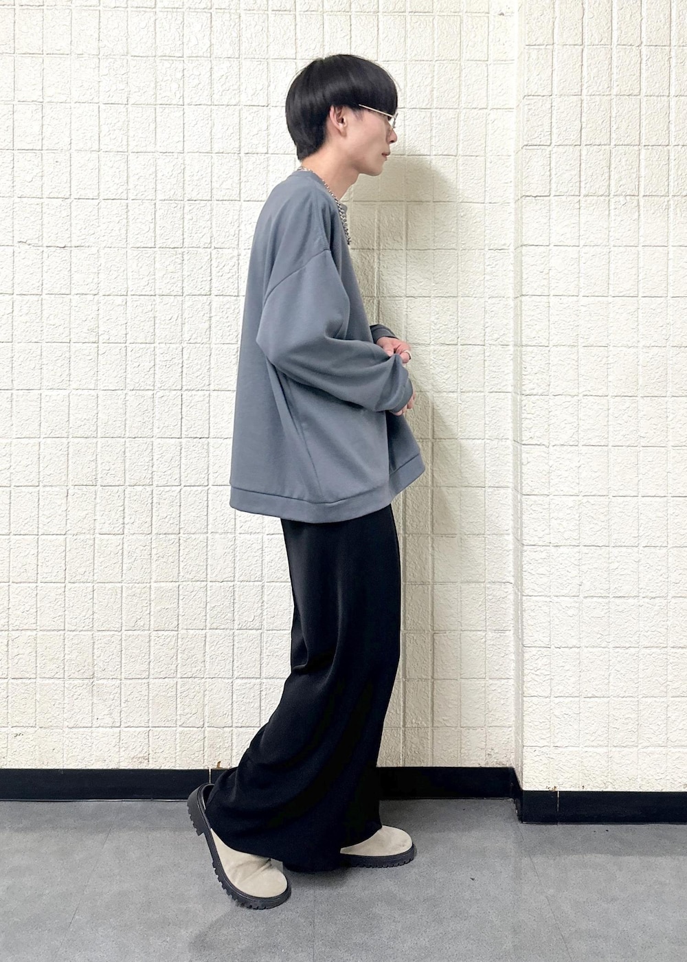 グレー系のTシャツ/カットソー、ブラック系のスラックス、シルバー系のリングを着用したメンズの春コーディネートの5枚目の写真