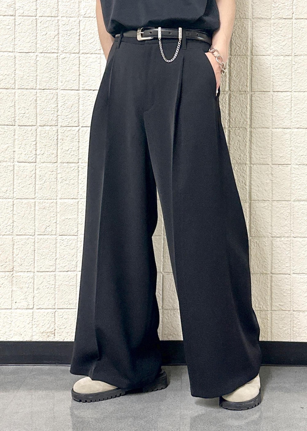 グレー系のTシャツ/カットソー、ブラック系のスラックス、シルバー系のリングを着用したメンズの春コーディネートの9枚目の写真