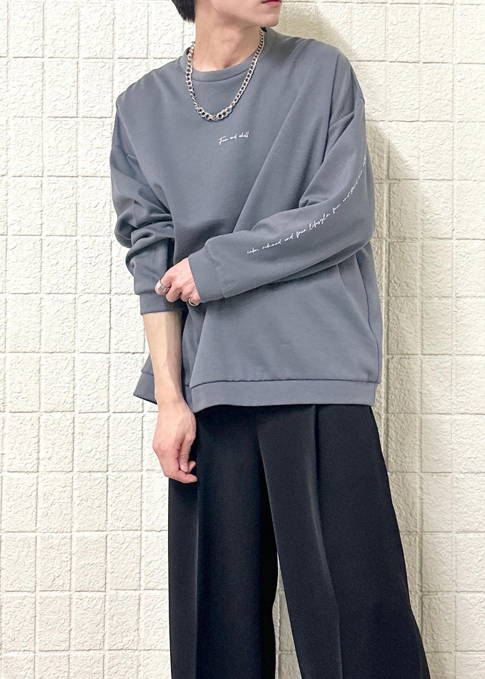 グレー系のTシャツ/カットソー、ブラック系のスラックス、シルバー系のリングを着用したメンズの春コーディネートの6枚目の写真