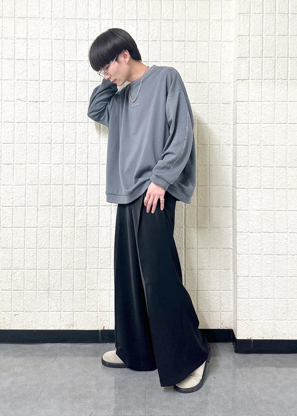 グレー系のTシャツ/カットソー、ブラック系のスラックス、シルバー系のリングを着用したメンズの春コーディネートの2枚目の写真