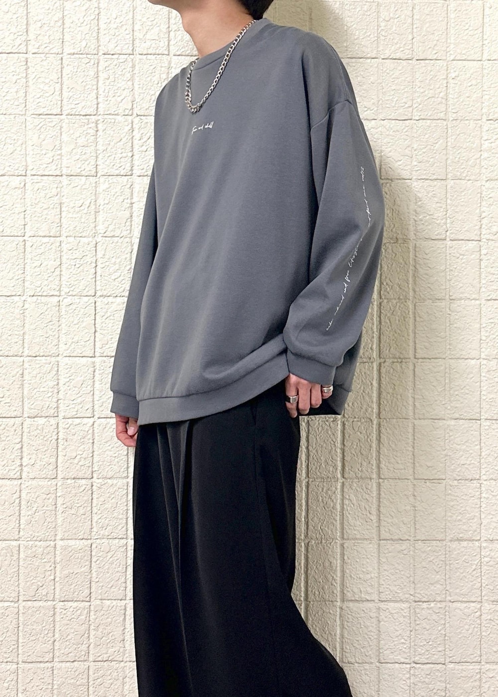 グレー系のTシャツ/カットソー、ブラック系のスラックス、シルバー系のリングを着用したメンズの春コーディネートの7枚目の写真