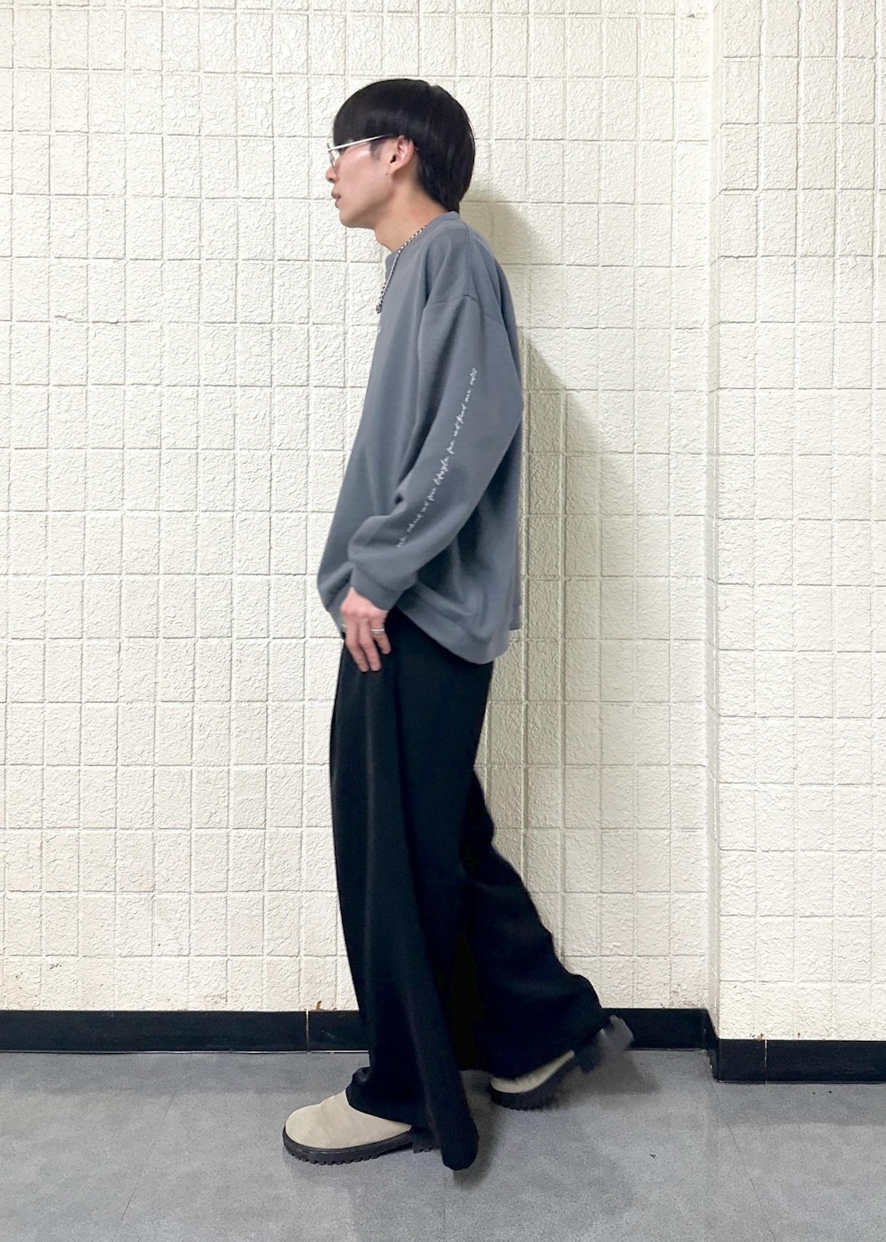 グレー系のTシャツ/カットソー、ブラック系のスラックス、シルバー系のリングを着用したメンズの春コーディネートの3枚目の写真